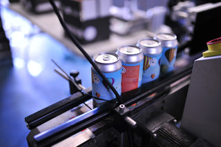 Cans moving through the labeling machine at Hammerton Brewery, preparing for packaging and distribution.