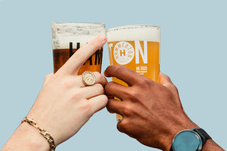 Hands clinking pint glasses in a cheers at Hammerton Brewery, filled with fresh beer.